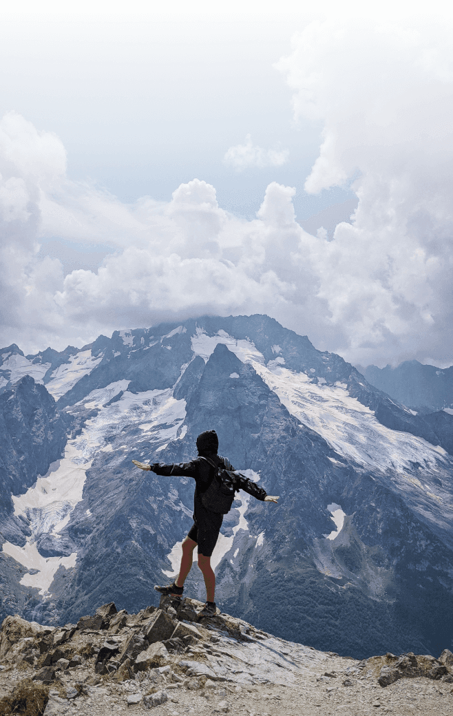 Person balancing on a rocky ledge at the mountain summit