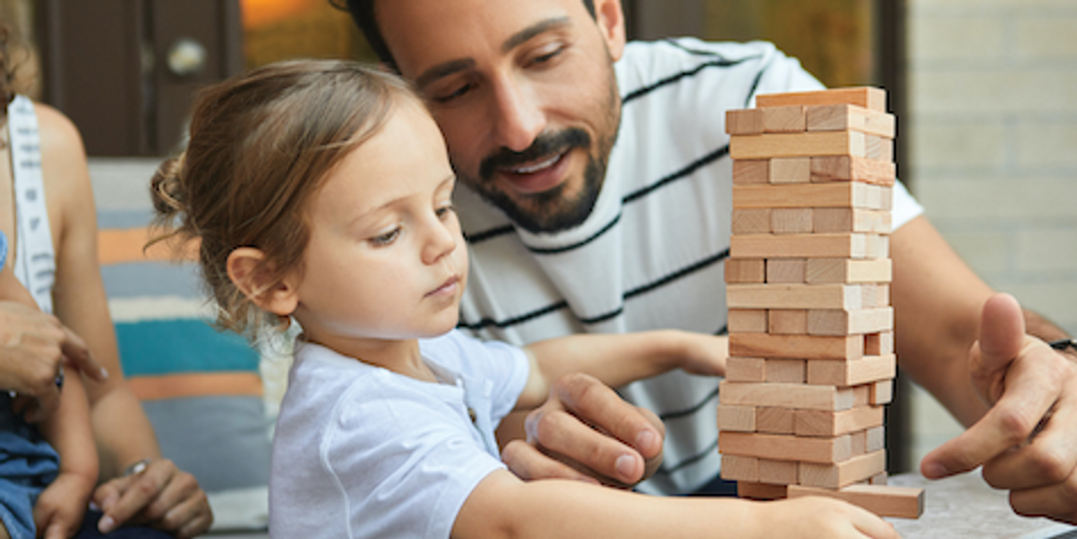 An adult playing Jenga with a child
