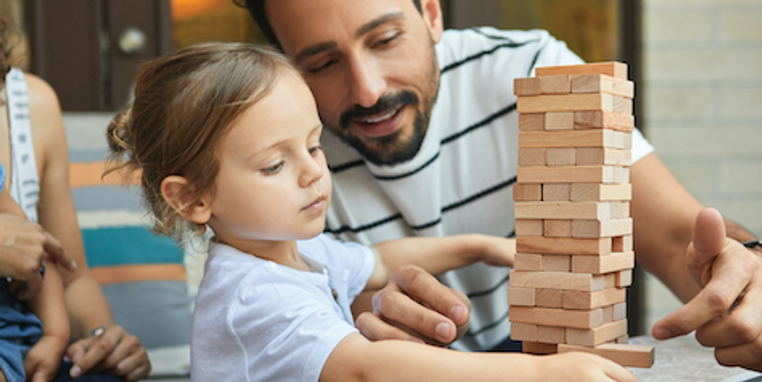 An adult playing Jenga with a child